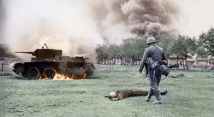 A Dead Soldier Lies In Front Of A Burning Tank
