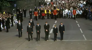 Men In Suits Followed By Large Crowd