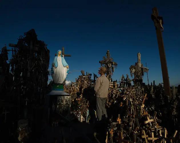 Man Praying In Front Of Virgin Mary Statue