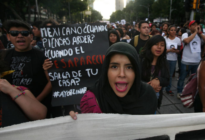 Protester holds sign reading "Mexicans, when will you burn?"