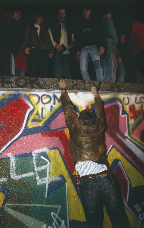 Civilian Hangs On Fallen Berlin Wall
