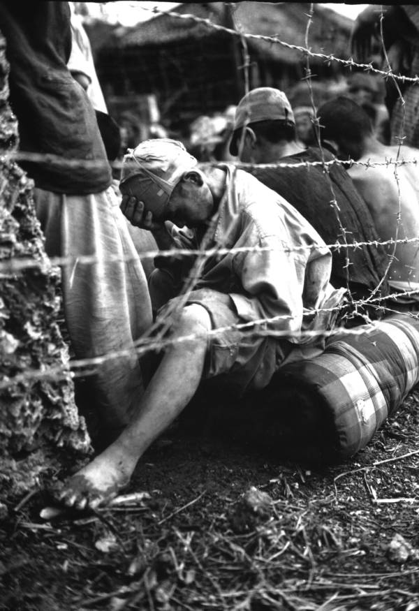 Japanese prisoner of war sits barbed wire