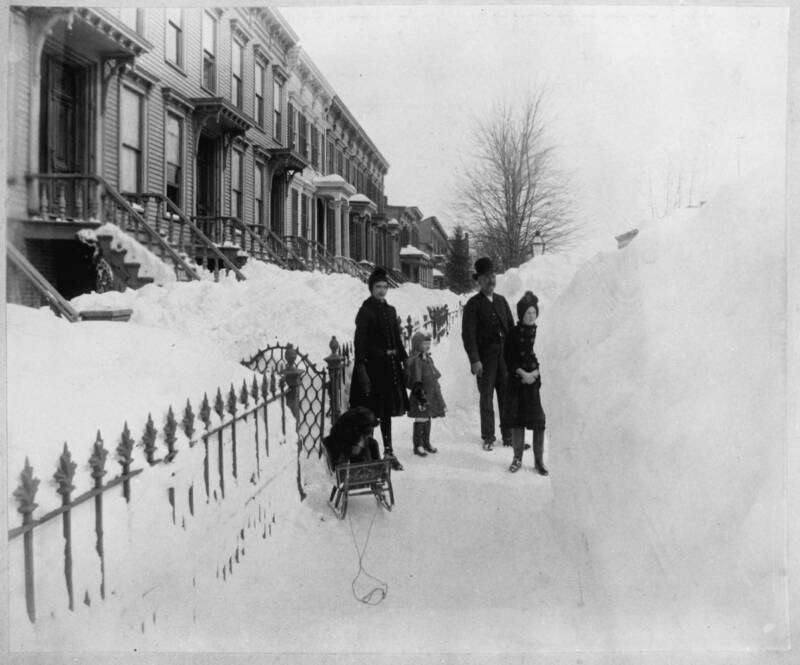 Family Outside Their Home Looking At A Wall Of Snow