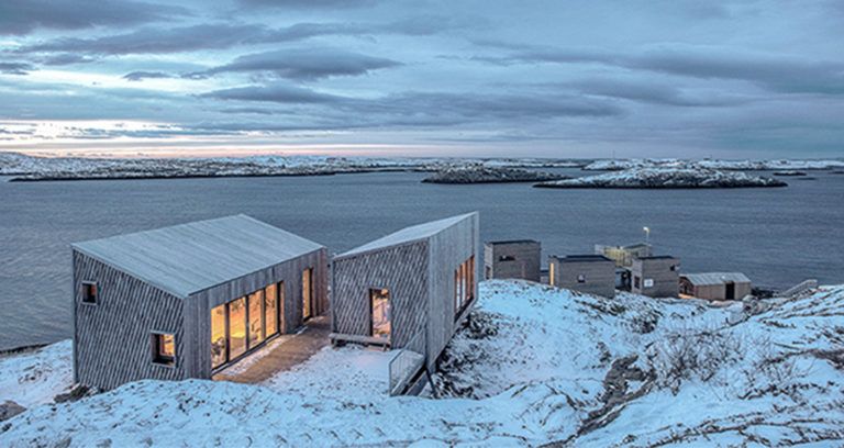 Lit Cabins In Snow By Water Featured