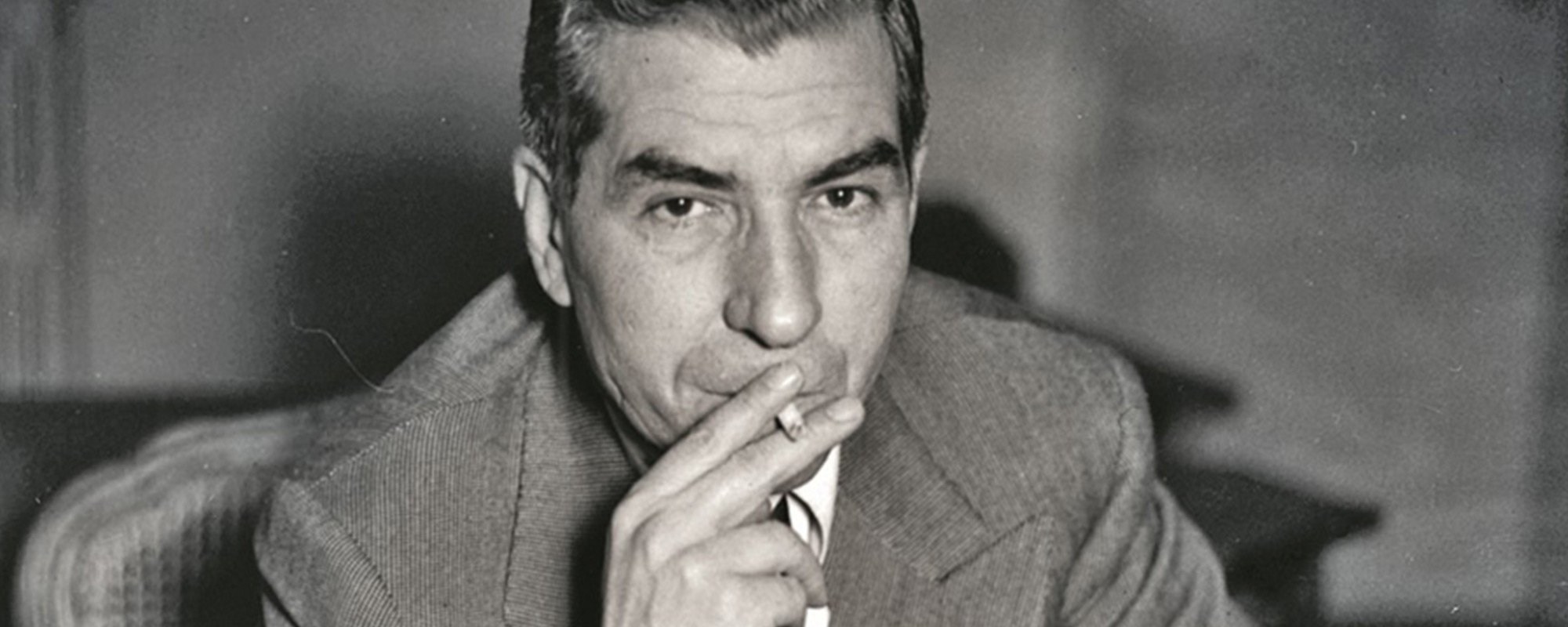 Luciano Smoking Into Camera Featured