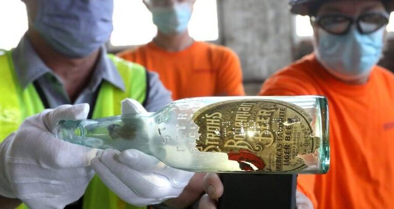 Three Workers Surrounding Bottle