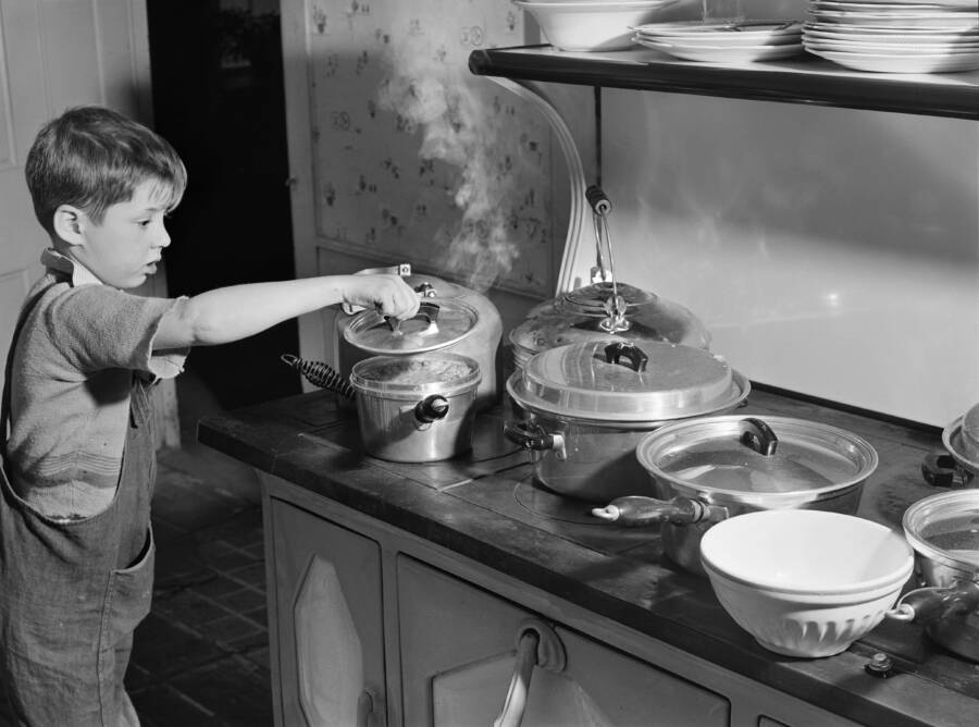 Young Boy Checking Pots On The Stove